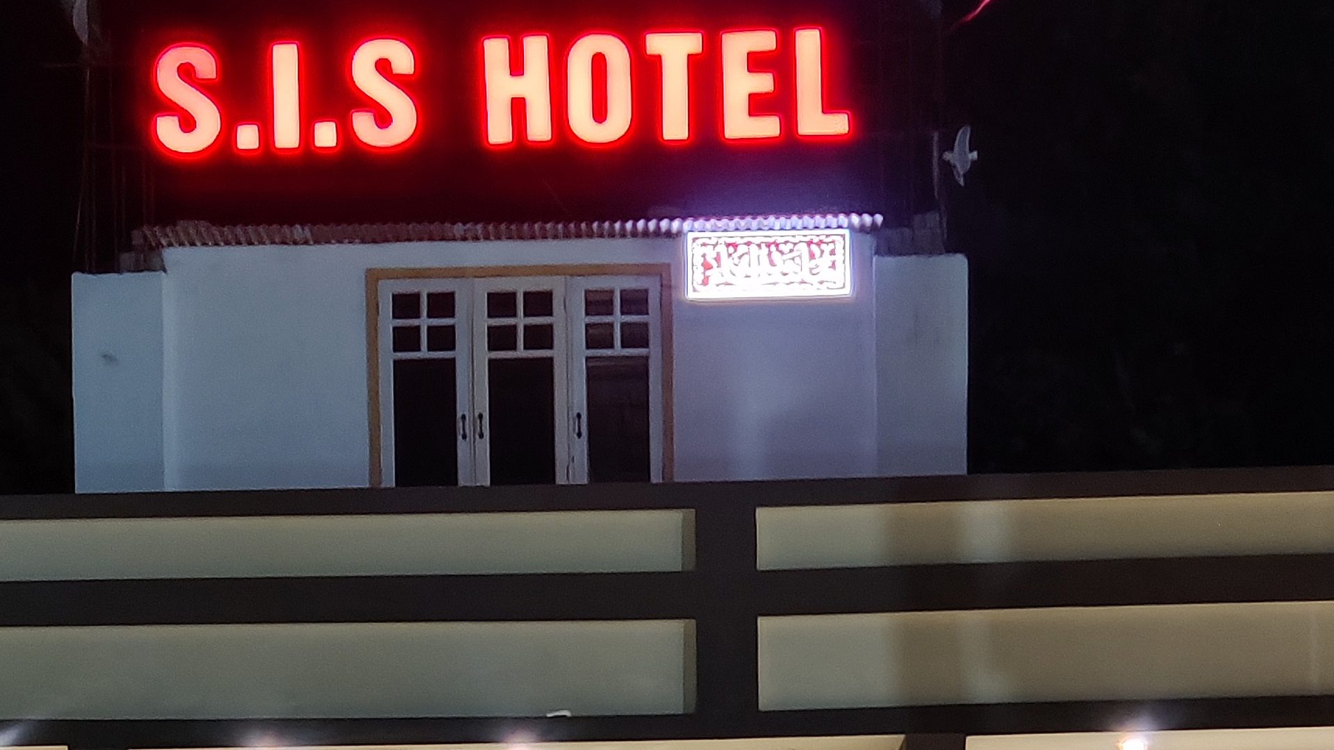 S.I.S Hotel sign lit up at night